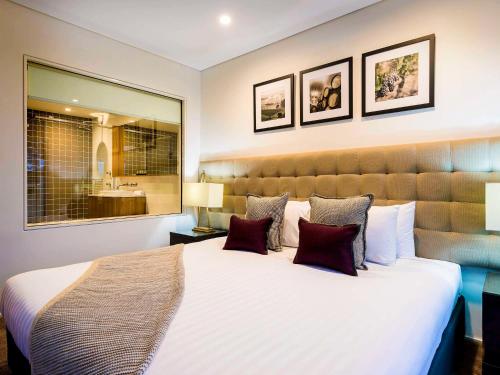una camera da letto con un grande letto bianco con cuscini di Grand Mercure the Vintage, Accor Vacation Club Apartments a Rothbury