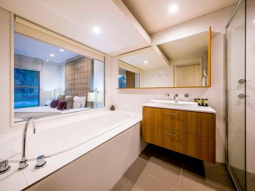 a bathroom with a tub and a sink and a mirror at Grand Mercure the Vintage, Accor Vacation Club Apartments in Rothbury