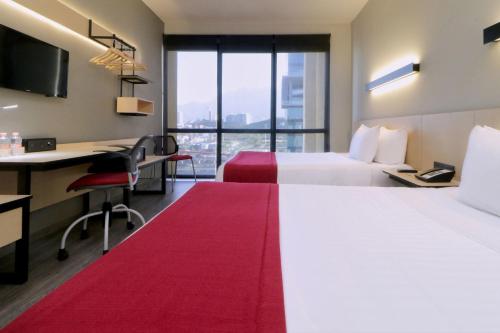 een hotelkamer met 2 bedden en een bureau bij City Express Plus by Marriott Monterrey Galerías in Monterrey