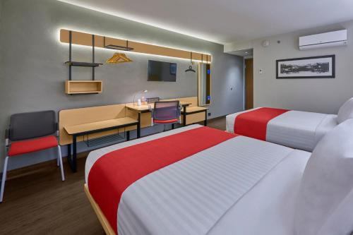 a hotel room with two beds and a desk at City Express by Marriott Hermosillo Expo in Hermosillo