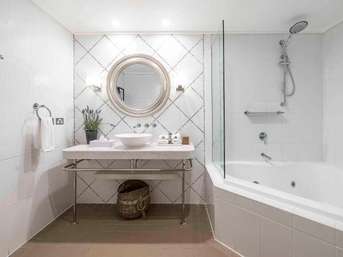 a bathroom with a sink and a tub and a mirror at The Sebel Bowral Heritage Park in Bowral