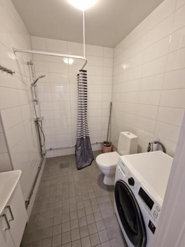 a bathroom with a toilet and a washing machine in it at Home Inn UPG76 in Stockholm