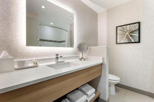 a bathroom with a sink and a mirror and a toilet at Best Western Premier Route 97 Vernon in Vernon