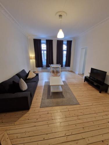ein Wohnzimmer mit einem schwarzen Sofa und einem Tisch in der Unterkunft Home Inn UPG76 in Stockholm