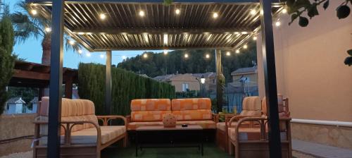 un patio con sofá y sillas bajo una pérgola en LES NINES, en Calpe