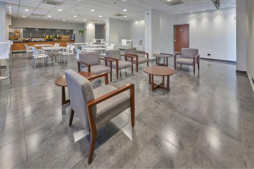 a waiting room with tables and chairs and tablesktop at City Express by Marriott Irapuato Norte in Irapuato
