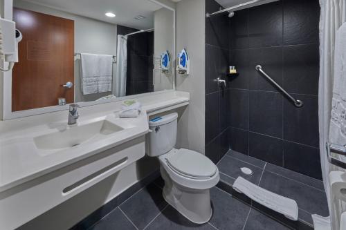 a bathroom with a toilet and a sink and a shower at City Express by Marriott Irapuato Norte in Irapuato