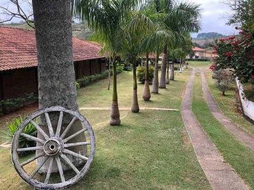 an old wagon wheel sitting next to a row of palm trees at Pousada Girassol 2 in Poços de Caldas