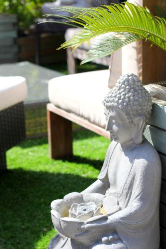 a statue of a woman sitting on the grass next to a bench at Ô Villagio Hôtel in Villeneuve-Loubet