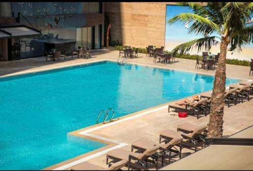 uma grande piscina com cadeiras e palmeiras em luxuary apartment in a 5-star hotel em Istambul