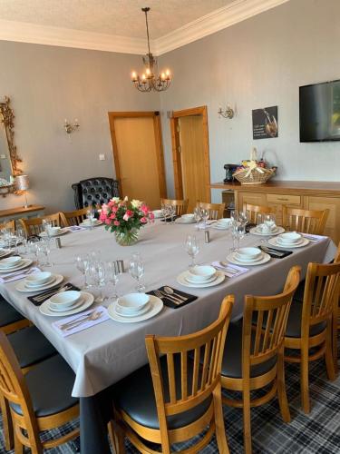 a long table with chairs and plates and wine glasses at Chandlers Country House in Rothesay