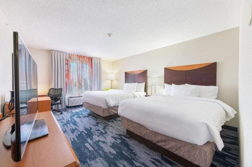 a hotel room with two beds and a flat screen tv at Fairfield Inn & Suites by Marriott Chicago Naperville in Naperville
