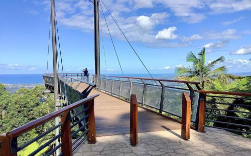 a person standing on a suspension bridge over the ocean at Jacaranda Villa Korora Beach NSW in Kororo Basin