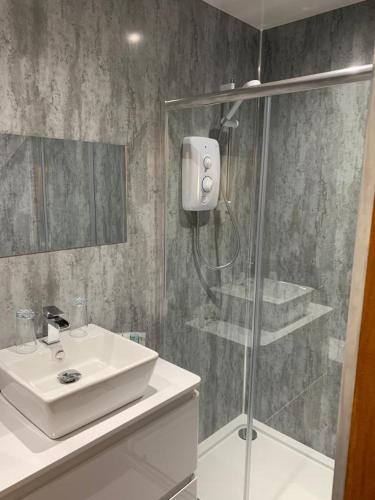 a bathroom with a sink and a glass shower at Chandlers Country House in Rothesay