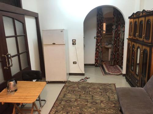 ein Wohnzimmer mit einem Tisch und einem Kühlschrank in der Unterkunft Zagazig in Manshīyat as Sādāt