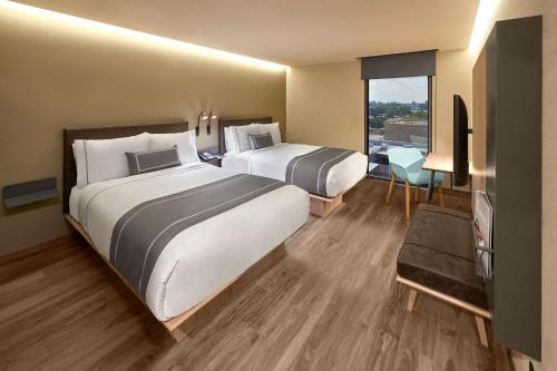 a hotel room with two beds and a television at City Express Plus by Marriott Tampico in Tampico