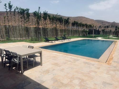 einen Pool mit einem Tisch und Stühlen sowie einem Tisch und Stühlen in der Unterkunft Villa dream oujda in Oujda