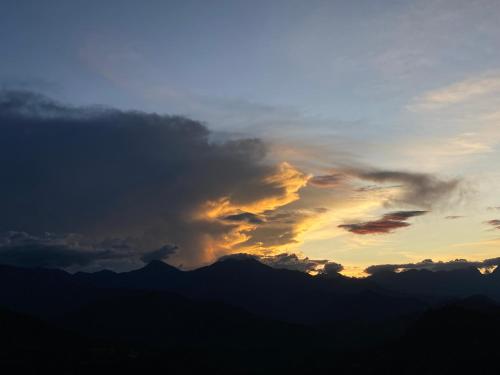 a sunset with clouds and mountains in the background at Origlamping Noche De Luna in Jardin