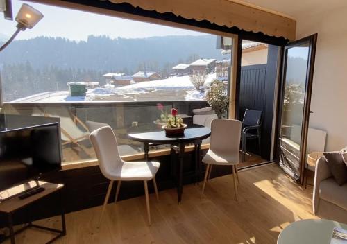 a room with a table and chairs and a large window at Studio lumineux avec vue sur le Mont Blanc in Cordon