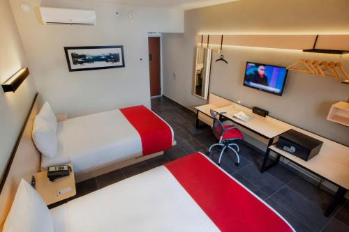 Habitación de hotel con cama y escritorio con ordenador en City Express Plus by Marriott Cabo San Lucas en Cabo San Lucas