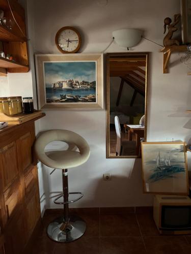 a room with a chair and a clock and a mirror at The Cozy Attic Stay in Herceg-Novi