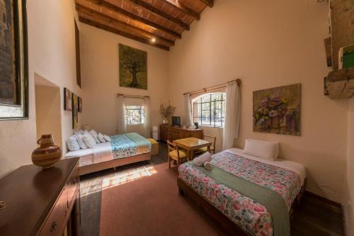 メキシコシティにあるMeztli: Casa Boutique & Spaのベッドルーム1室(ベッド2台、デスク、テーブル付)