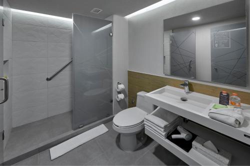 a bathroom with a toilet and a sink and a shower at City Express Plus by Marriott Merida in Mérida