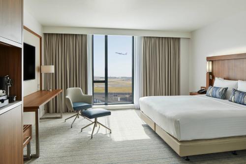 a hotel room with a bed and a desk and a window at Courtyard by Marriott London Heathrow Airport in Hayes