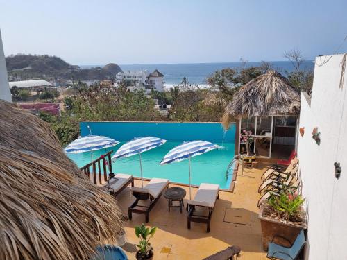 希伯萊特沙灘的住宿－Namasté Zipolite Suites，享有带遮阳伞的游泳池的景色