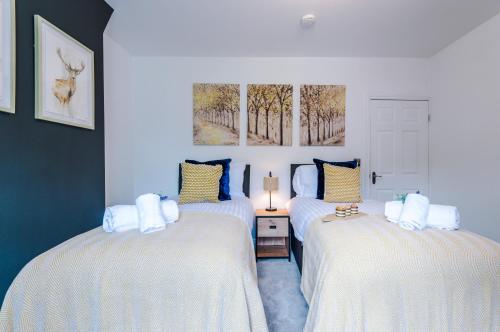 um quarto com 2 camas com lençóis brancos e uma janela em Spacious 3-bed home in Nantwich by 53 Degrees Property - Amazing location, Ideal for Groups - Sleeps 6 em Nantwich