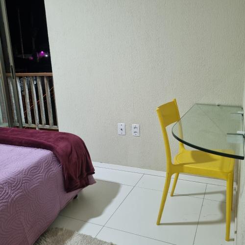 a bedroom with a glass table and a yellow chair at Apartamento Dei Fiori in Guaramiranga