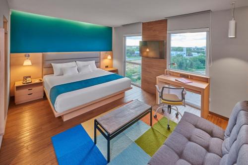 una camera d'albergo con letto, scrivania e sedia di City Express Suites by Marriott Silao Aeropuerto a Silao