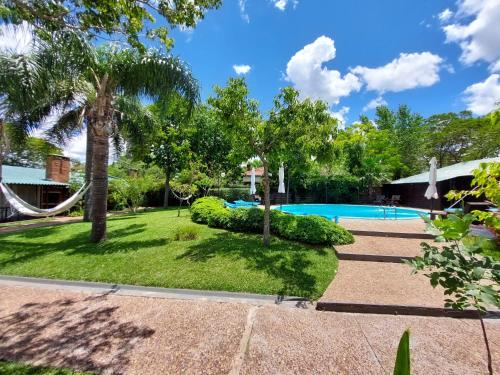 un cortile con piscina e alberi di Hotel Jardines de Dayman a Termas del Daymán