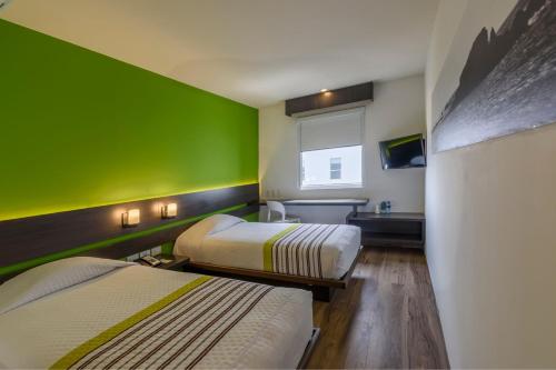 Habitación con 2 camas y pared verde. en City Express Junior by Marriott Bogota Aeropuerto, en Bogotá