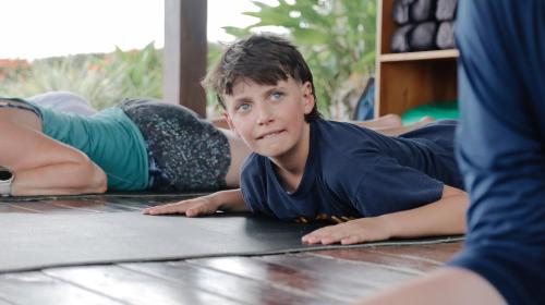 a young boy is laying on the floor at Surf Synergy All-Inclusive Surf and Wellness Retreat in Jacó