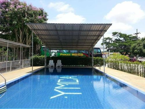 - une piscine avec 2 chaises sous un auvent dans l'établissement YMCA International Hotel Chiangrai, à Ban Fang Min