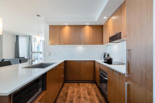 a large kitchen with wooden cabinets and a sink at Level Vancouver Yaletown Seymour in Vancouver