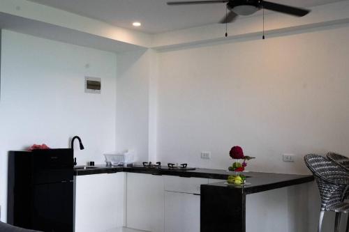 a kitchen with white cabinets and a black refrigerator at Tablas Seaview Homestay in Ferrol