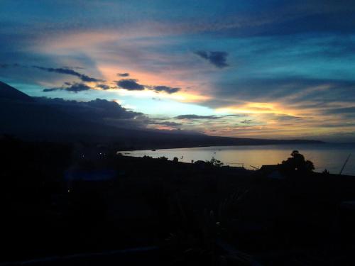 a sunset over a body of water with at Sony Home Stay in Amed