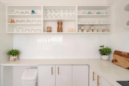a white kitchen with white cabinets and shelves at Kalua Holiday Apartments in Maroochydore