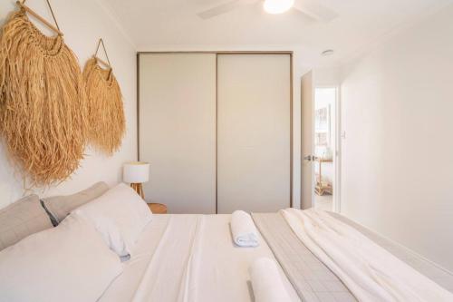 a white bedroom with a white bed and a window at Kalua Holiday Apartments in Maroochydore