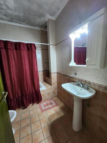 a bathroom with a sink and a red shower curtain at Excelente Departamento Centrico in San Pedro