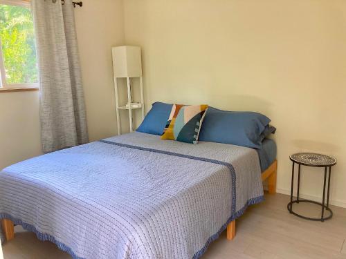 a bedroom with a bed with blue sheets and a window at Seaside House and Aloha Bungalow in Pahoa