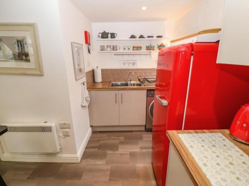 eine kleine Küche mit einem roten Kühlschrank und einer Spüle in der Unterkunft Riverside Cottage in Amlwch