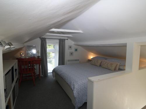 a bedroom with a bed and a table and a window at Riverside Cottage in Amlwch