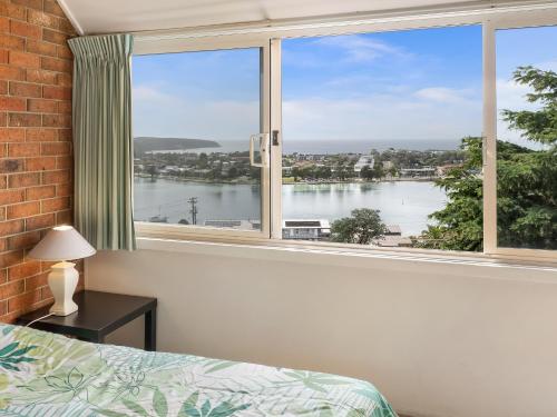 a bedroom with a large window with a view of the water at Pacific Heights in Merimbula