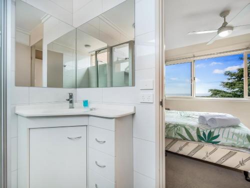 a white bathroom with a sink and a mirror at Pacific Heights in Merimbula