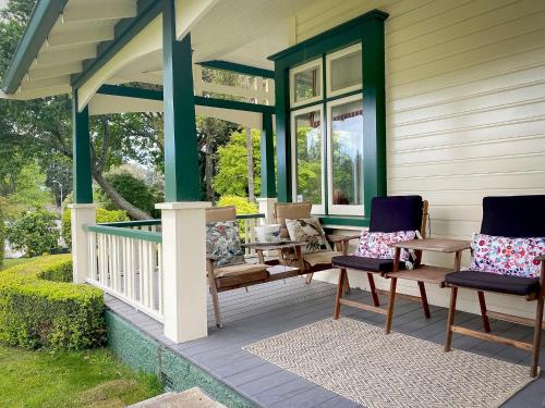 a porch with two chairs and a table at Gumnut House. in Whanganui