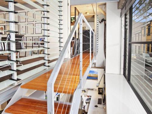 a staircase in a house with white walls and wooden floors at WAREHOUSE RARE!! MASSIVE LUXURY ARCHITECTURAL MASTERPIECE w HUGE PRIVATE ROOFTOP GARDEN WITH PANARAMIC CITY VIEWS in Sydney