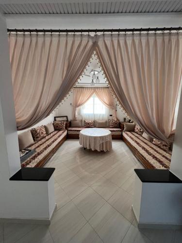- un salon avec une table et des rideaux dans l'établissement Résidence Talhaoui, à Saïdia